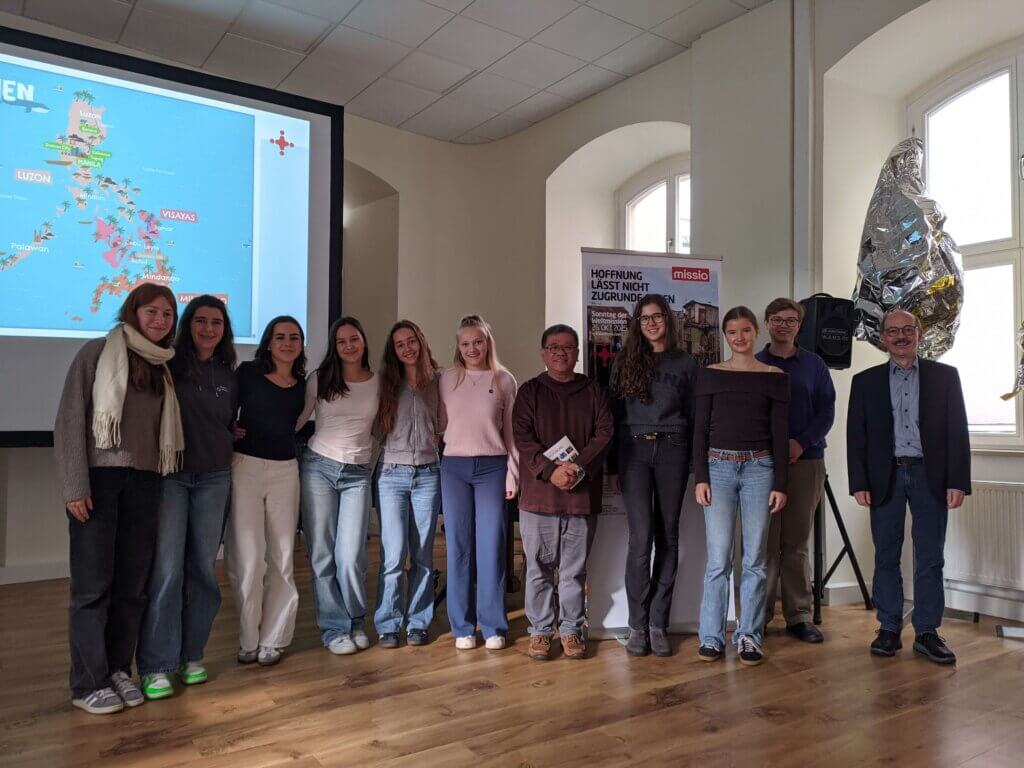 Schülerinnen aus der 11. Jahrgangsstufe des St.-Ursula-Gymnasiums (v.l.n.r.), Father Christian „Toots“ Buenafe, Alexander Tartler, Begleiter und Übersetzer des Referenten und Harald Retsch, Mitarbeiter der Schulleitung sowie Politiklehrer am St.-Ursula-Gymnasium nach dem Vortrag im Angelasaal der St.-Ursula-Schule.